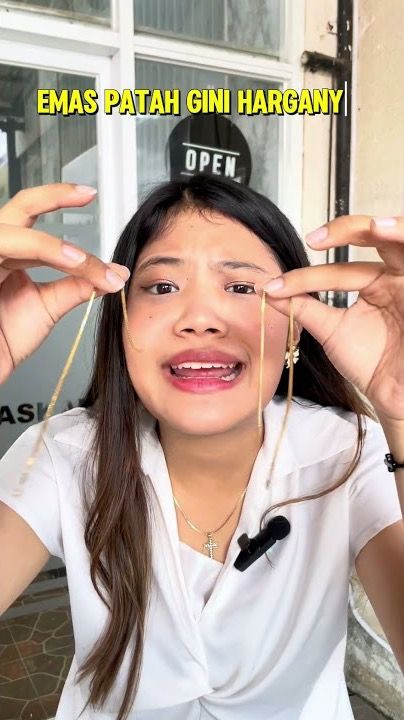 Perempuan memegang kalung emas yang patah, bertuliskan Emas patah gini harganya